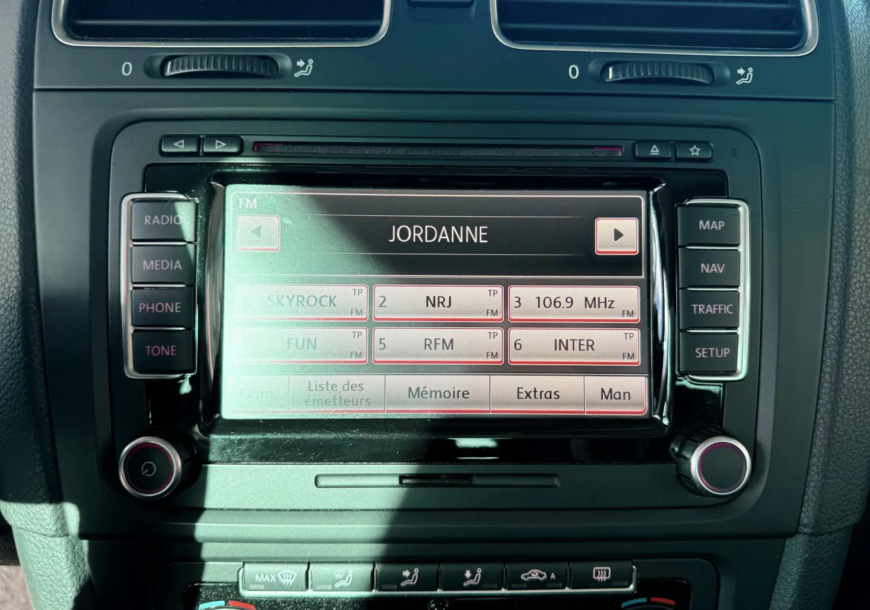 Écran central tactile de la Volkswagen Golf 1.4 TSI 2012 affichant les stations radio avec boutons de commande autour.