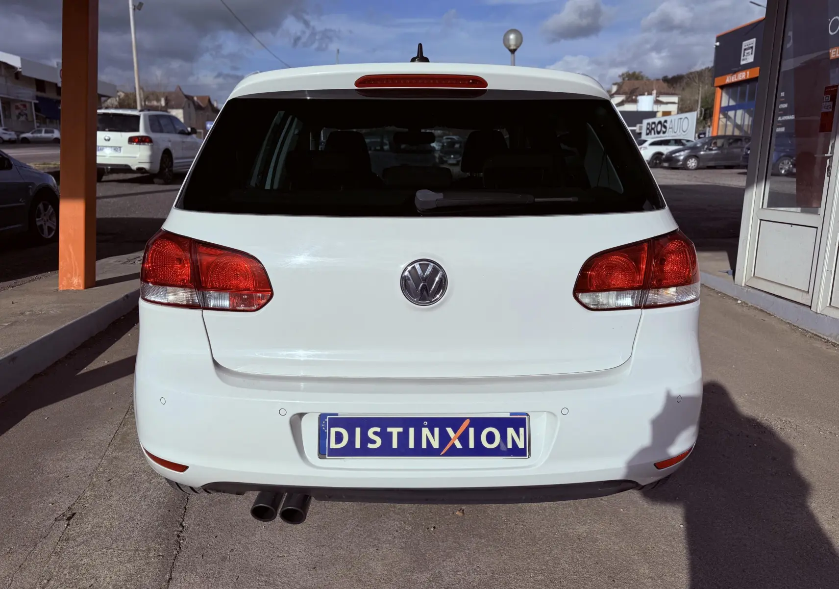 Vue arrière d'une Volkswagen Golf blanche de 2012, avec feux rouges et double sortie d'échappement visible.