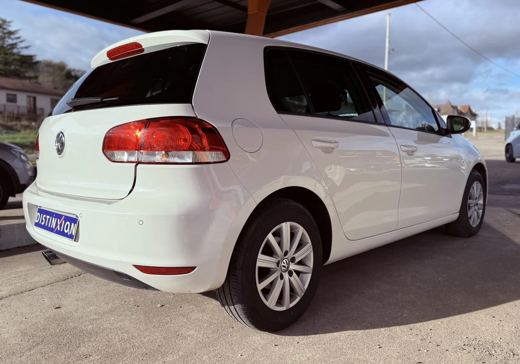 Volkswagen Golf blanche vue de trois quarts arrière droit, avec feux arrière et jantes alliage visibles.