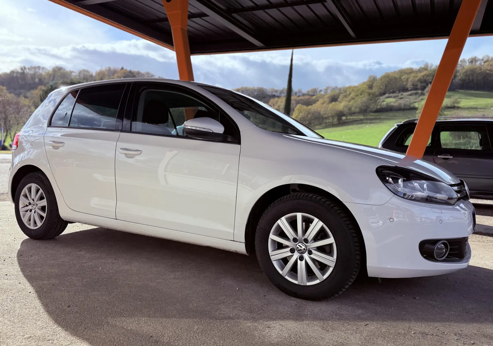 Volkswagen Golf 1.4 TSI blanche vue de profil côté gauche sous abri avec jantes alliage et feux avant visibles.