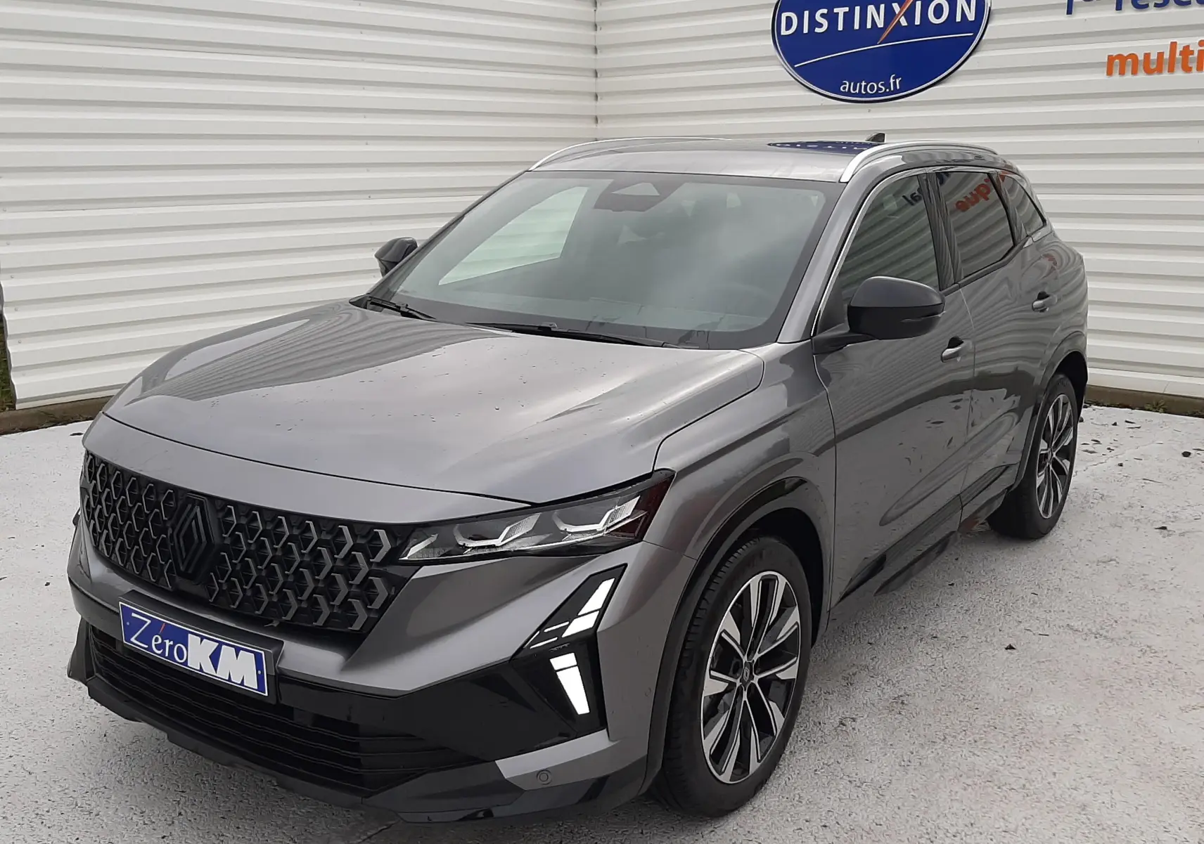 Renault Austral Ph.2 gris schiste en 3/4 avant droit, avec calandre noire distinctive et feux LED verticaux allumés.