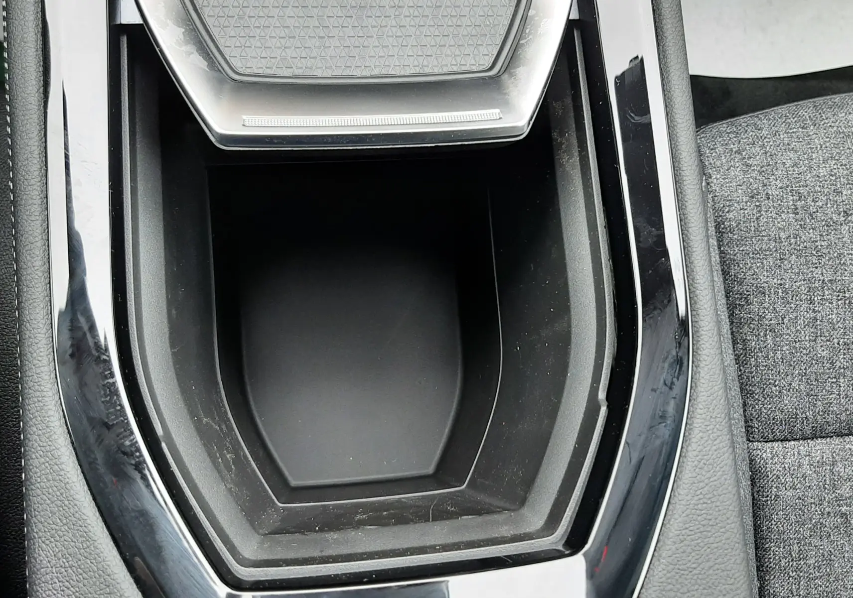 Gros plan sur la console centrale noire brillante du Renault Austral Ph.2 gris schiste, avec un espace de rangement vide.