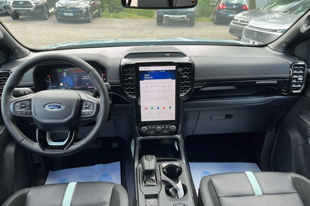 Vue intérieure avant du Ford Ranger Stormtrak 2026 avec tableau de bord noir et écran tactile vertical central.