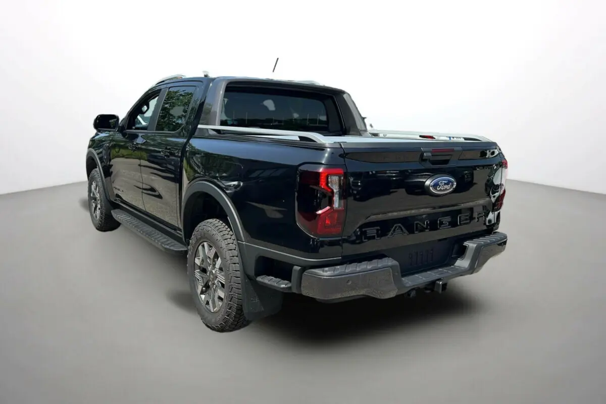 Vue 3/4 arrière droite du Ford Ranger noir agate avec benne et barres de toit visibles.