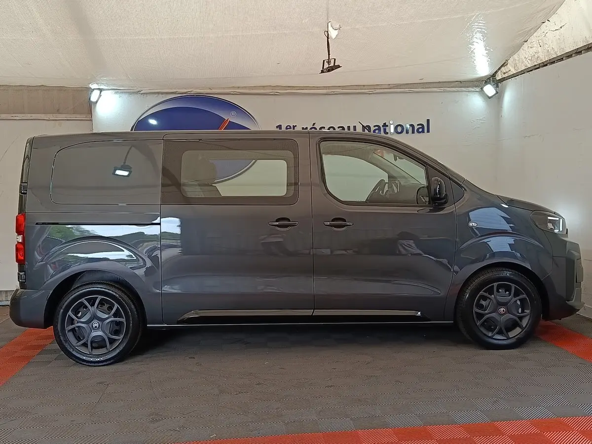 Vue de profil côté gauche d'un Citroën Jumpy gris foncé 2025 avec vitres latérales et jantes noires.