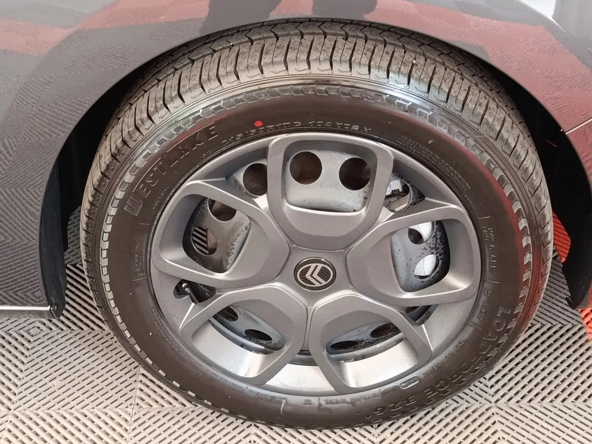 Gros plan sur la roue arrière droite d’un Citroën Jumpy gris foncé, montrant le pneu et l’aile du véhicule.