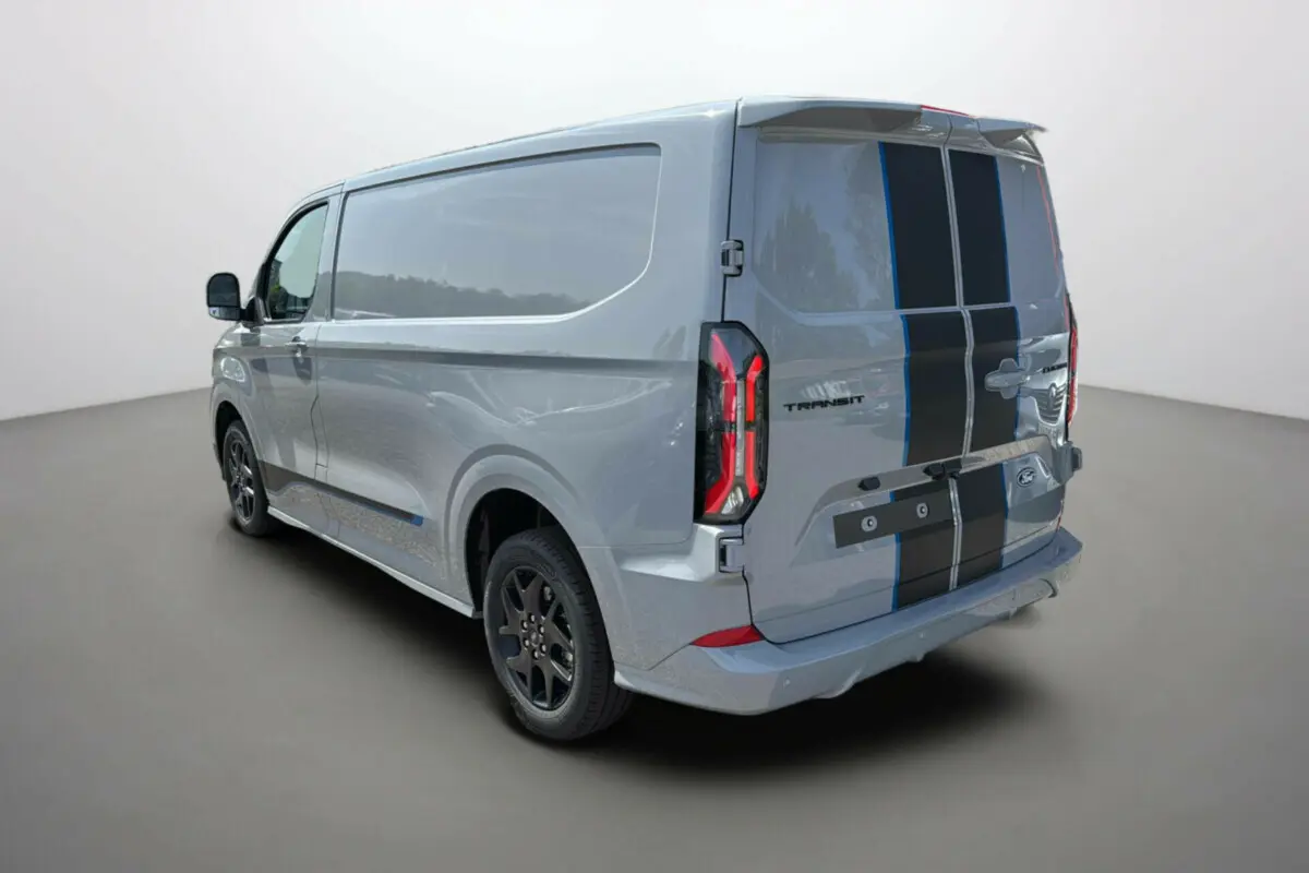 Vue 3/4 arrière droite du Ford Transit Fourgon Custom gris mat avec bandes noires sportives et jantes alu noires.