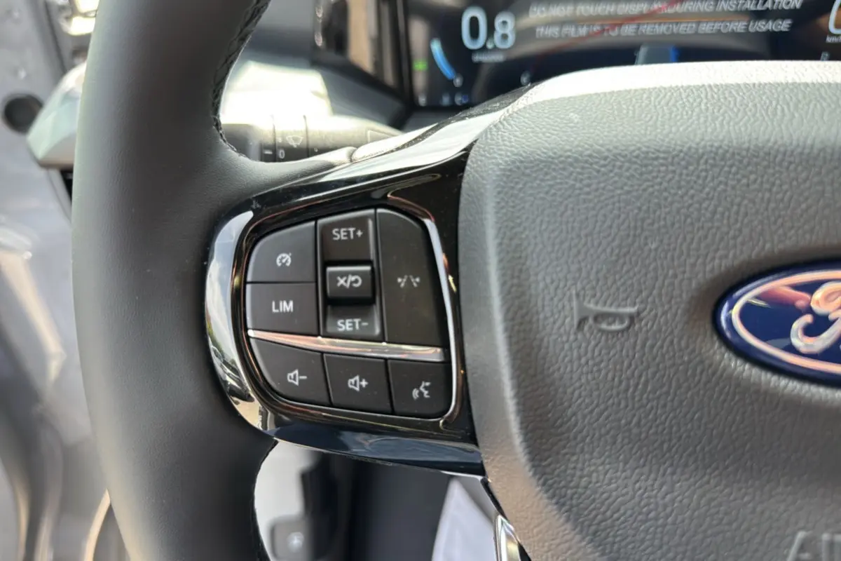 Gros plan sur le volant multifonctions gris du Ford Transit Fourgon Custom 170 BVA8 Sport 2026 avec commandes intégrées.