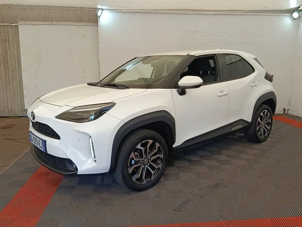 Toyota Yaris Cross blanc vue 3/4 avant droit, avec jantes alliage noires et protections plastiques noires.