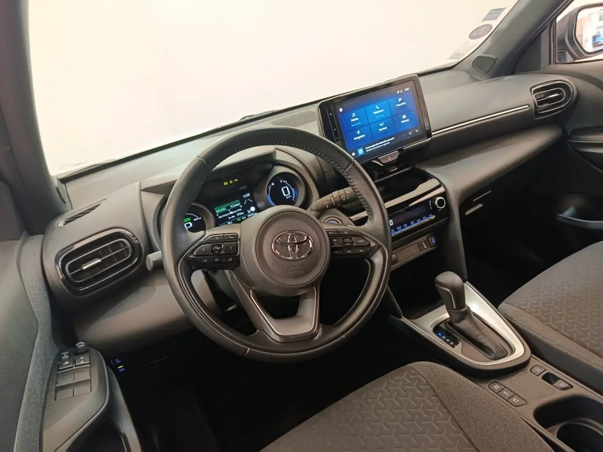 Vue intérieure côté conducteur du Toyota Yaris Cross 1.5 Hybrid 2022, volant cuir et écran tactile central.