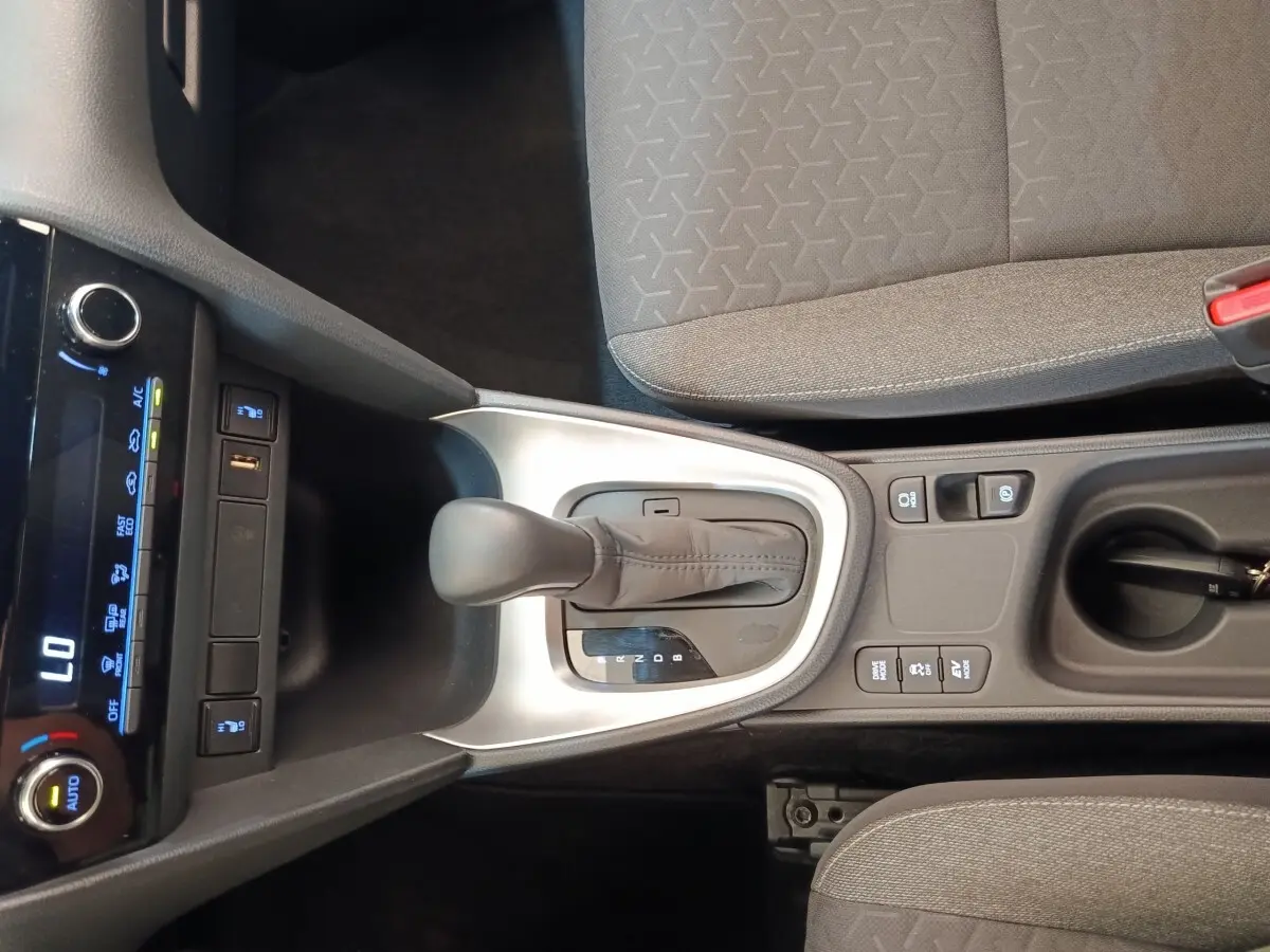 Vue plongeante sur la console centrale grise avec levier de vitesse automatique et sièges tissu gris du Toyota Yaris Cross blanc.