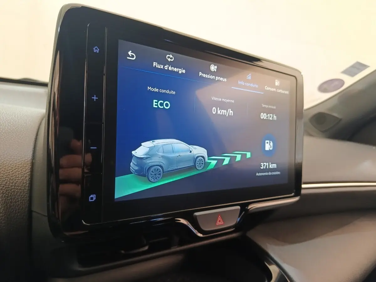 Écran tactile central affichant le mode ECO et l'autonomie de 371 km dans l'habitacle d'une Toyota Yaris Cross blanche.