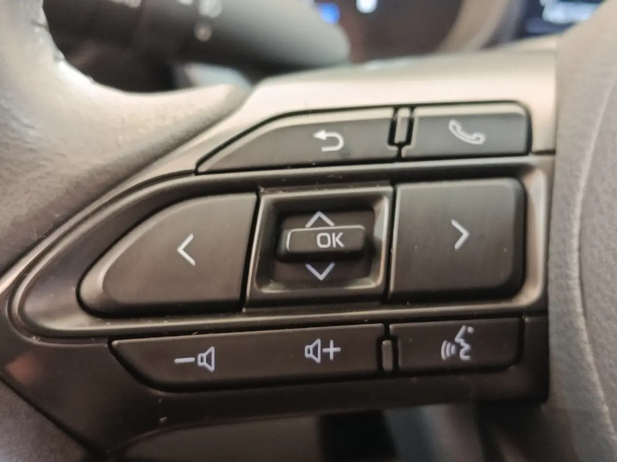 Gros plan sur les commandes multifonctions noires du volant de la Toyota Yaris Cross hybride blanche, version 2022.