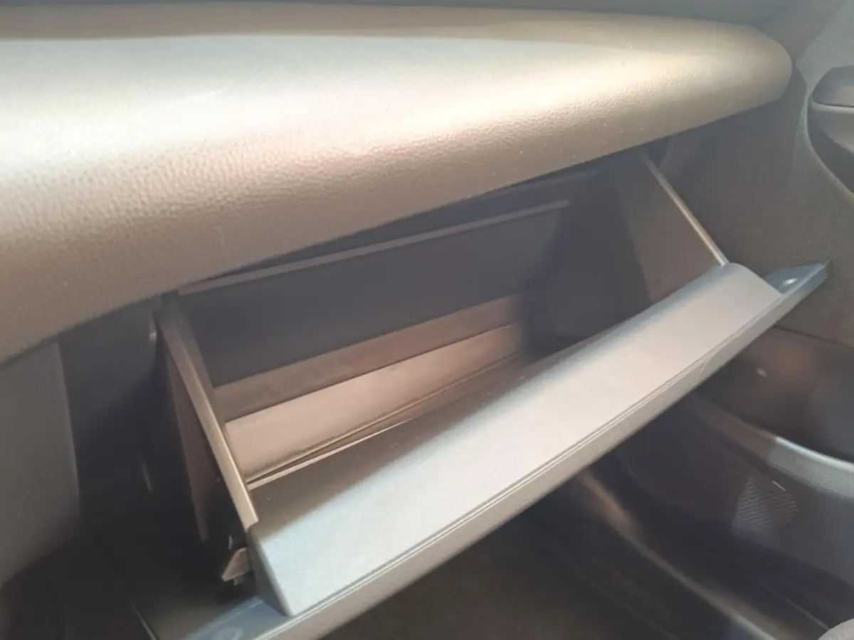 Gant de rangement ouvert côté passager de la Toyota Yaris Cross 1.5 Hybrid blanche, intérieur noir.