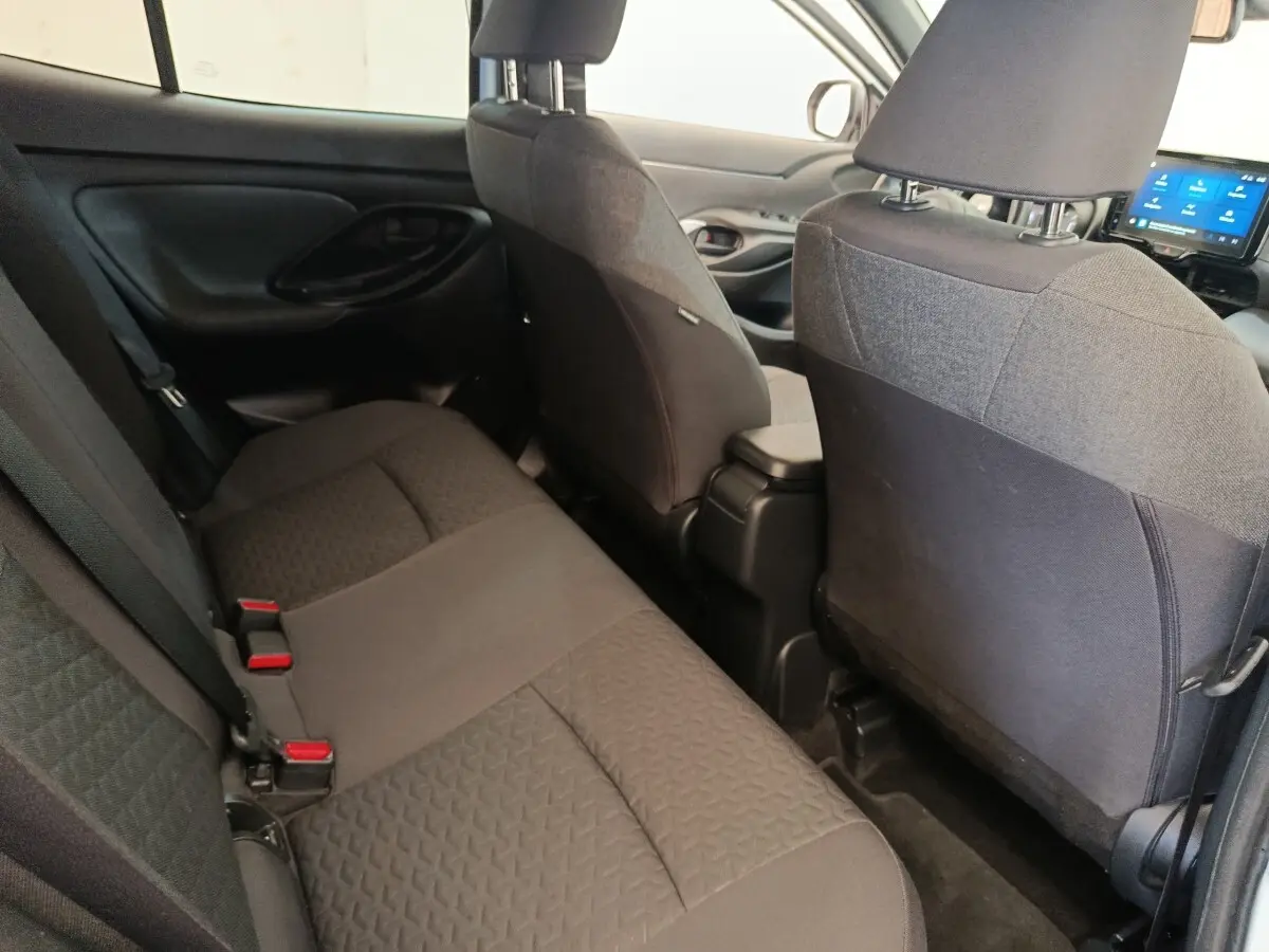 Vue intérieure arrière de la Toyota Yaris Cross 2022, sièges tissu gris foncé et tableau de bord avec écran tactile visible.