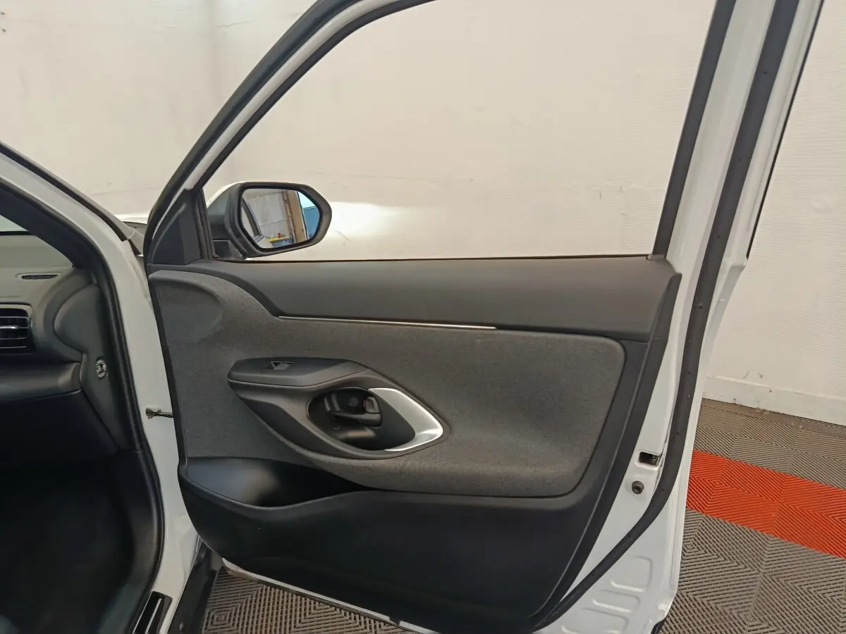 Vue intérieure de la porte avant gauche blanche d'une Toyota Yaris Cross 2022 avec garniture grise et noire.