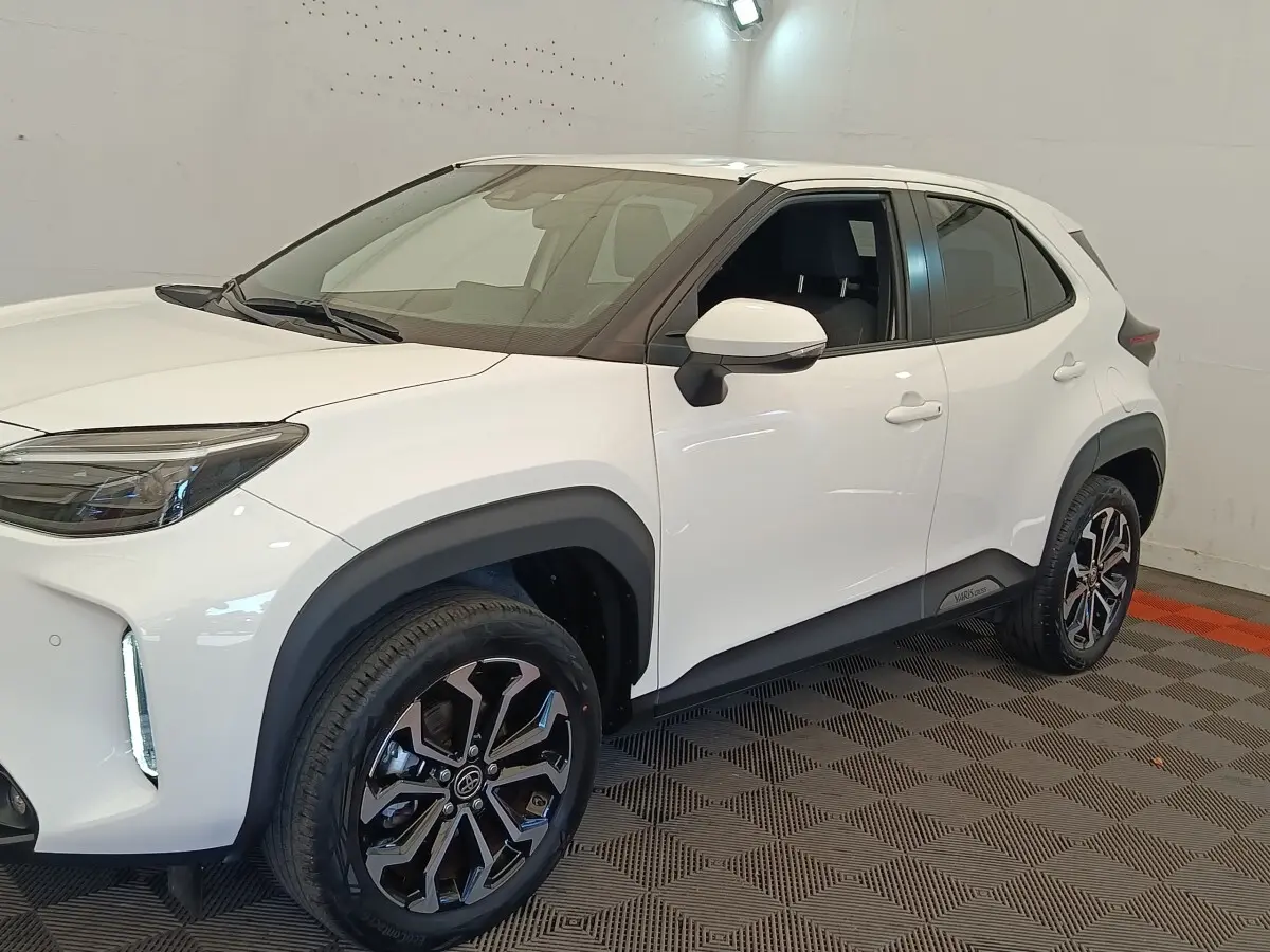 Toyota Yaris Cross blanc vue 3/4 avant droit, avec jantes noires et éléments de carrosserie noirs contrastants.