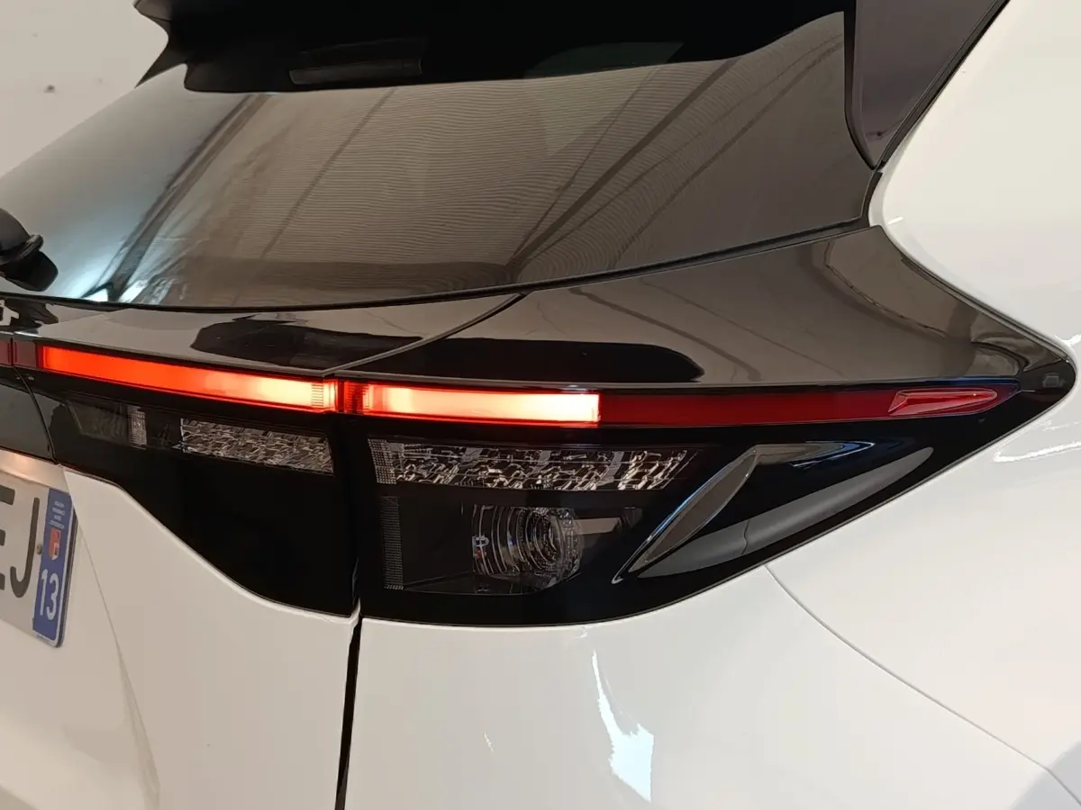 Gros plan sur le feu arrière droit allumé d’une Toyota Yaris Cross blanche, soulignant le contraste noir et blanc du hayon.