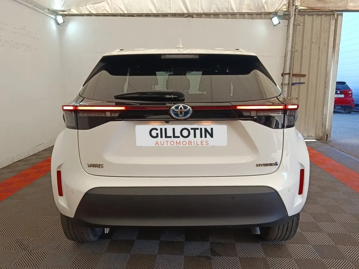 Vue arrière d'une Toyota Yaris Cross blanche hybride 2022 avec feux LED fins et logo Toyota central.