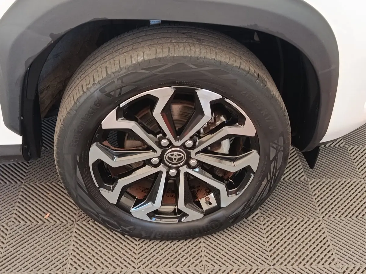 Gros plan sur la roue avant droite de la Toyota Yaris Cross blanche avec jante alliage noire et argentée.