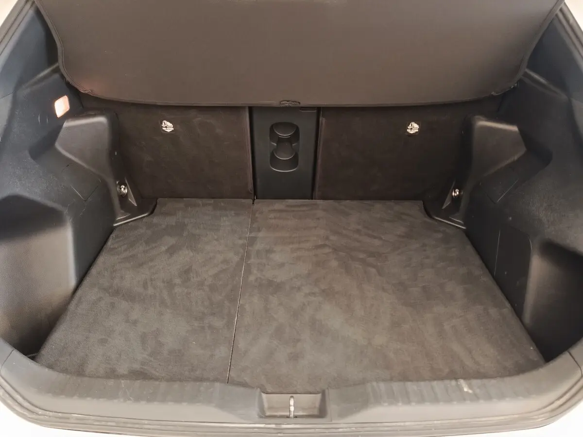 Coffre ouvert de la Toyota Yaris Cross blanc, vue intérieure montrant l’espace de chargement avec banquette arrière rabattue.
