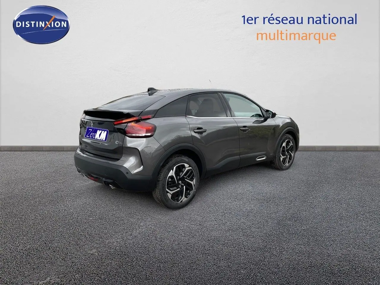 Citroën C4 gris platinium métal vue 3/4 arrière côté droit, avec jantes bicolores et toit noir contrasté.