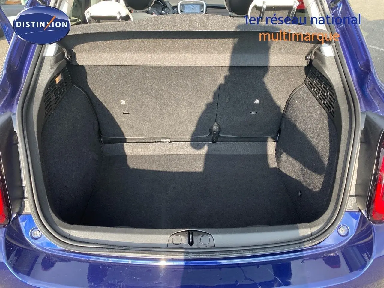 Coffre ouvert vu de l'arrière d'une FIAT 500X bleu Venezia Metal, montrant un espace de chargement propre et spacieux.