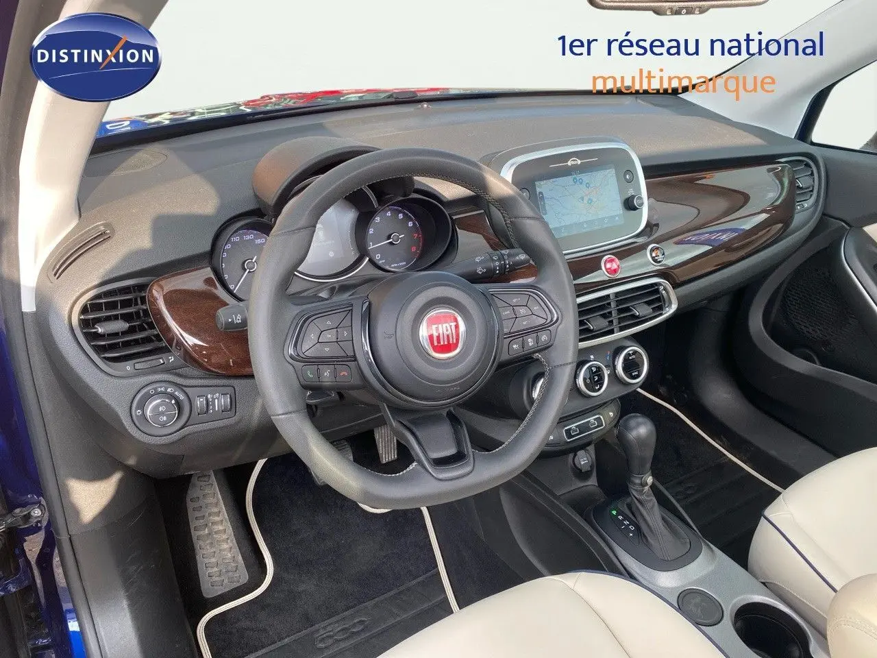 Intérieur de la Fiat 500X bleu Venezia, vue côté conducteur, tableau de bord avec écran tactile et cuir ivoire.