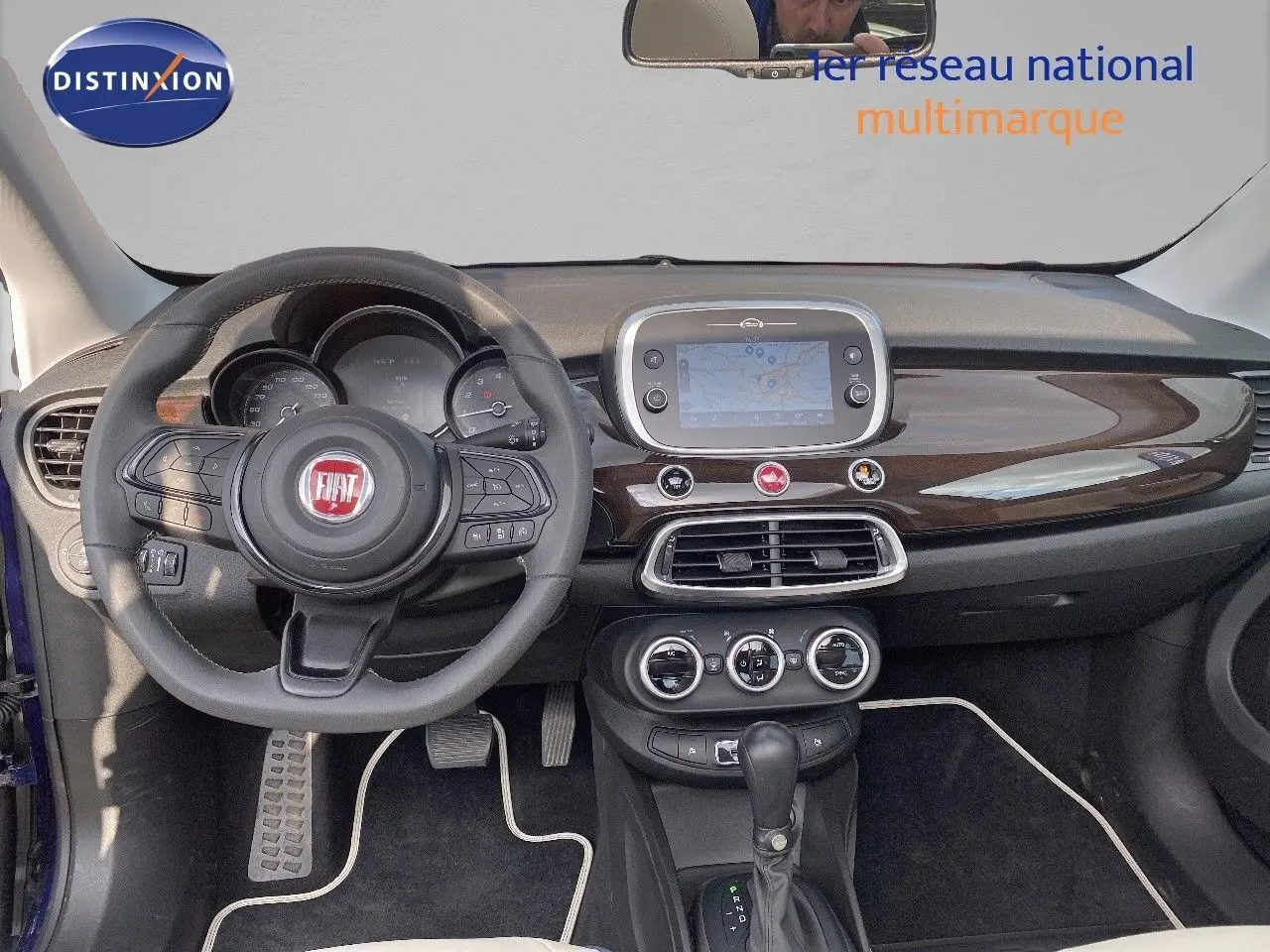 Vue intérieure frontale du tableau de bord du Fiat 500X bleu Venezia Metal avec volant multifonction et écran tactile central.