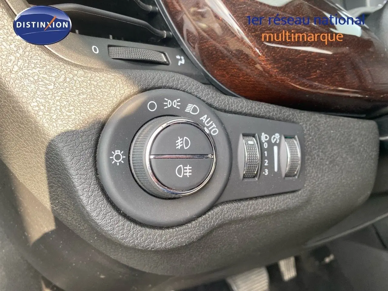 Gros plan sur la commande d'éclairage avec finition bois dans l'habitacle du Fiat 500X bleu Venezia 2021.