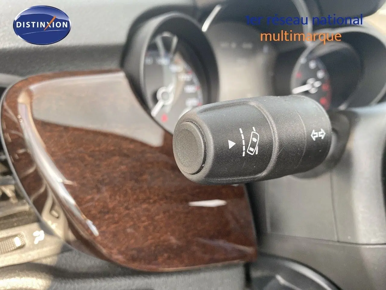 Gros plan sur la commande de régulateur de vitesse avec tableau de bord et insert bois foncé du Fiat 500X bleu Venezia Metal.