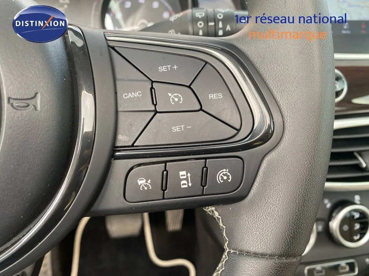 Gros plan sur les commandes de régulateur de vitesse au volant cuir d'une Fiat 500X 2021, finition Yacht Club Capri.