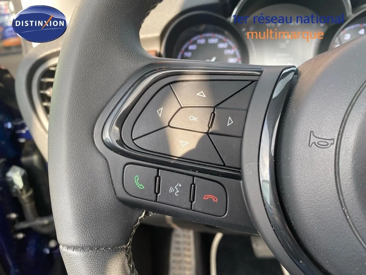 Gros plan sur les commandes au volant côté gauche d'une Fiat 500X bleu Venezia 2021, avec boutons de téléphone et navigation.