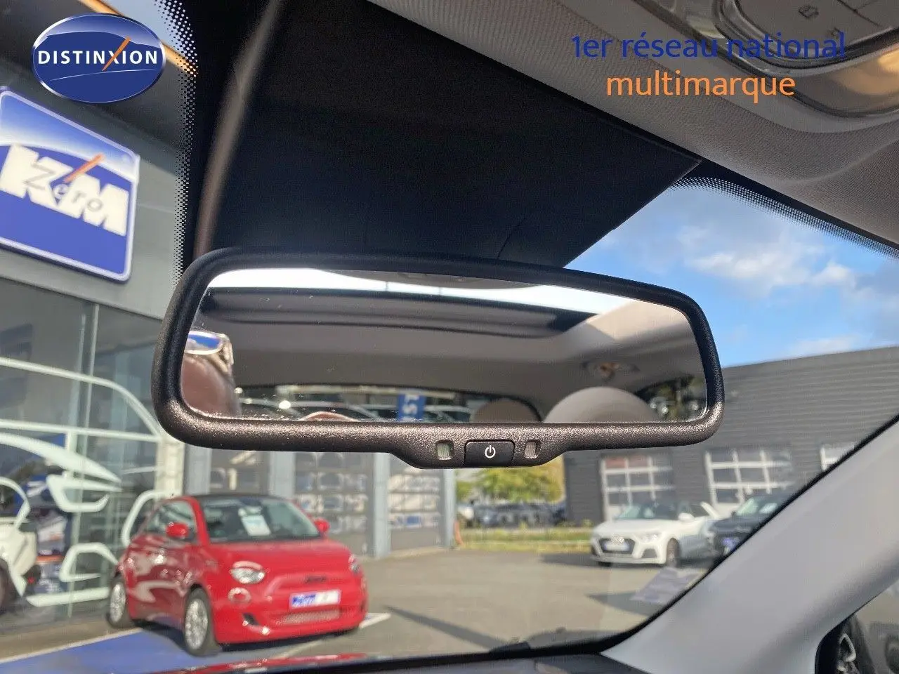 Reflet dans le rétroviseur intérieur montrant le toit ouvrant d'une Fiat 500X Bleu Venezia Metal vue de l'avant intérieur.