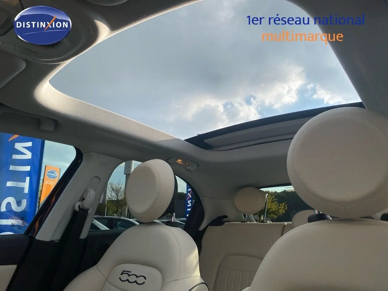 Vue intérieure du toit ouvrant panoramique et des sièges avant en cuir ivoire du Fiat 500X bleu Venezia Metal.