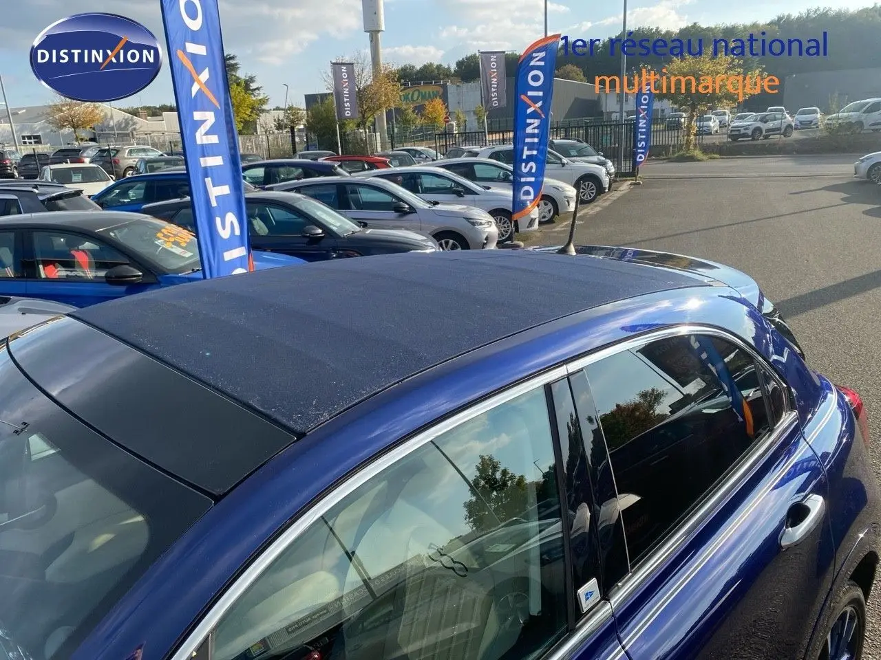 Vue latérale droite d'une FIAT 500X bleu Venezia Metal avec toit ouvrant en toile foncée, en extérieur sur parking.