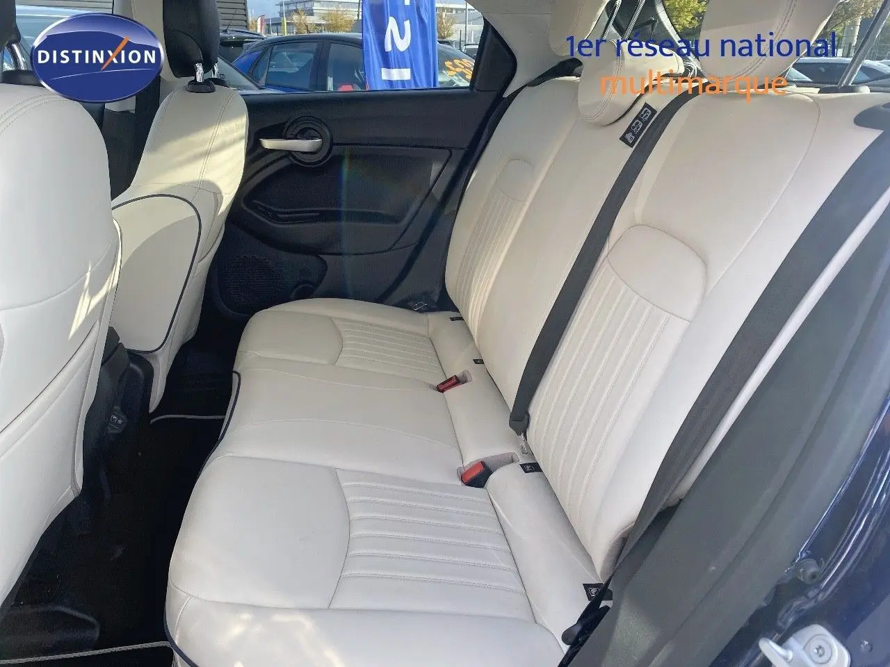 Vue côté droit de l'habitacle arrière d'une Fiat 500X 2021 avec sièges cuir ivoire et portières bleu Venezia métal.