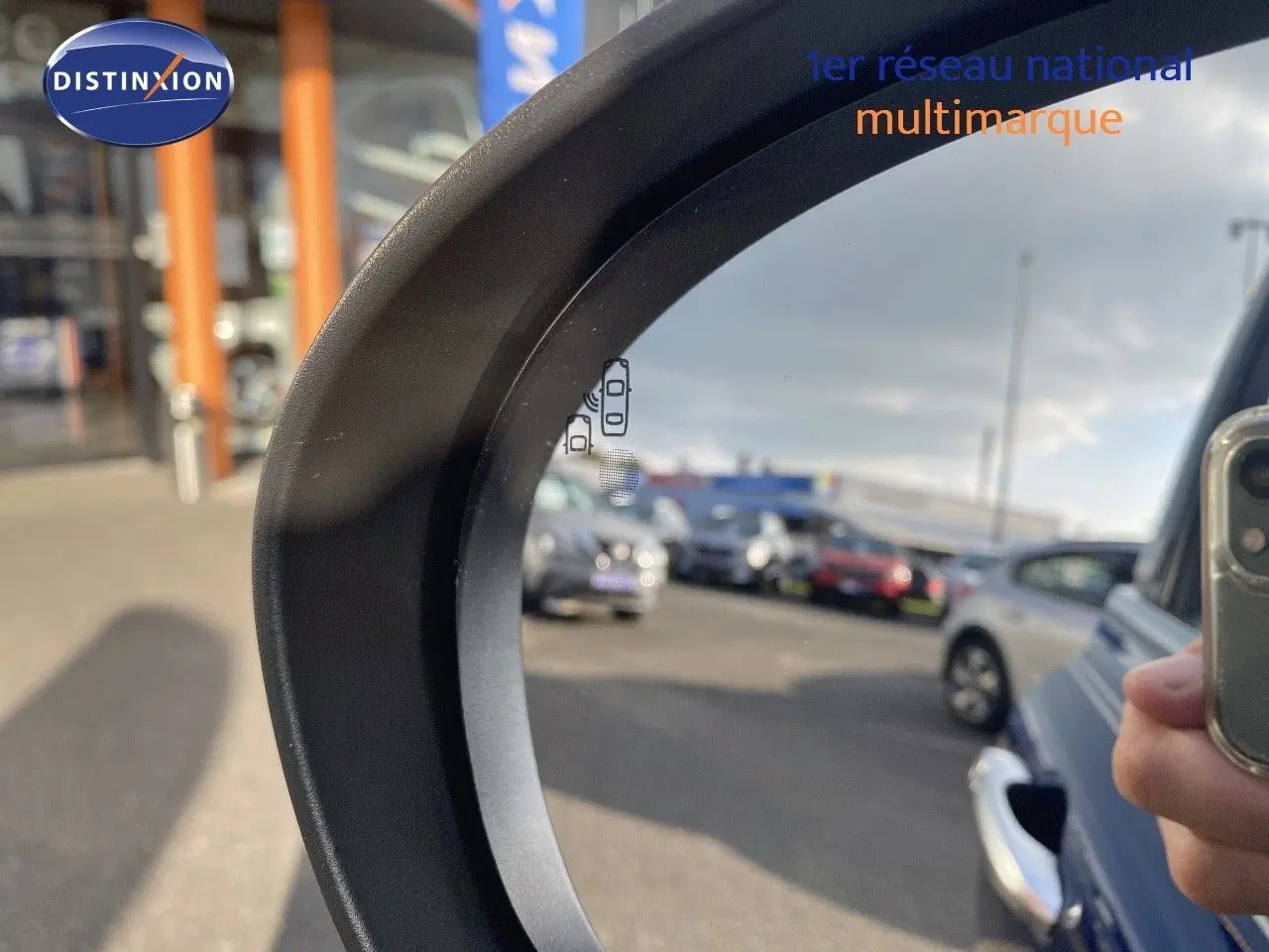 Rétroviseur côté droit montrant une FIAT 500X bleu Venezia metal en 3/4 arrière dans un parking.