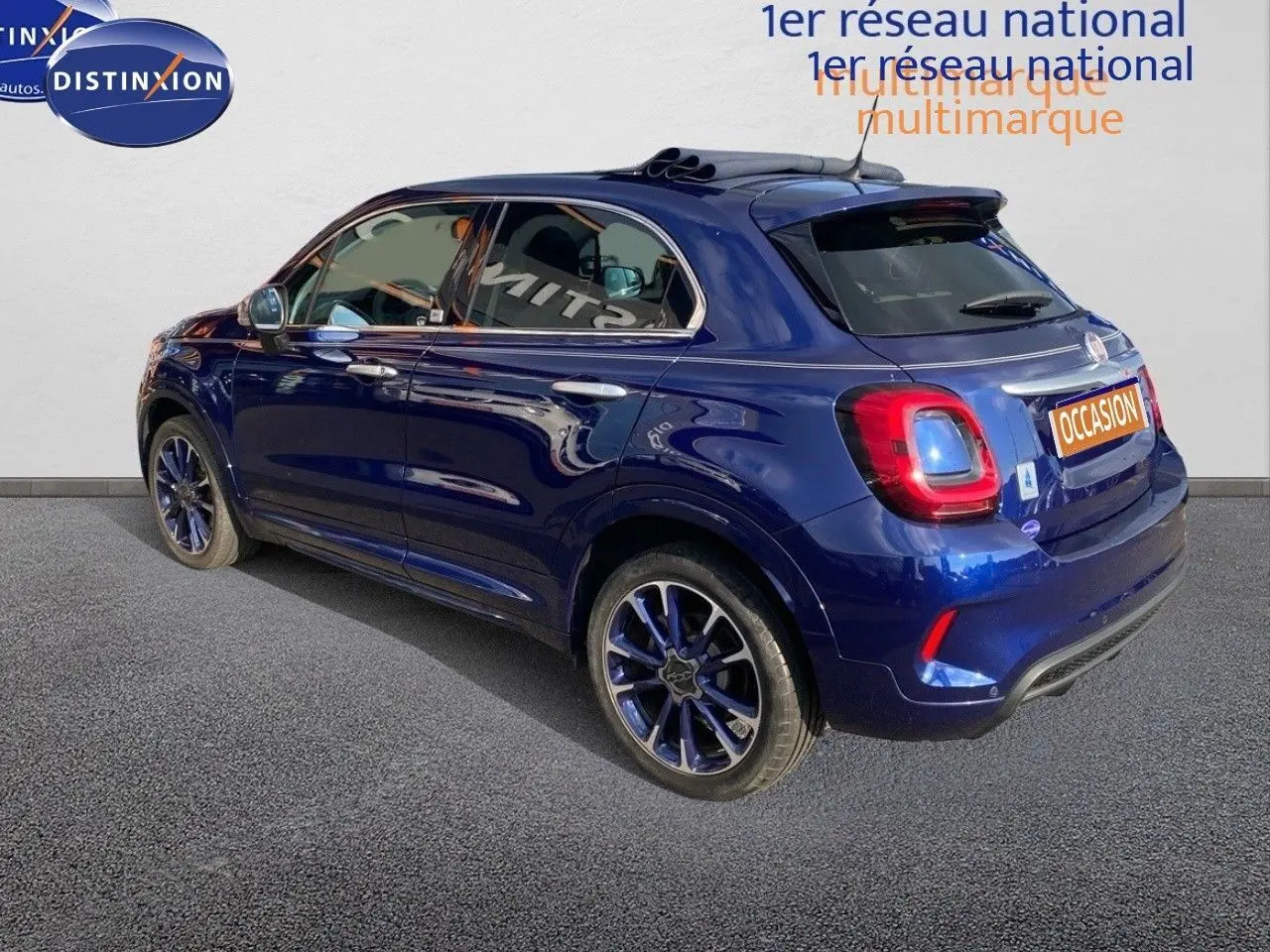Vue 3/4 arrière gauche d'une FIAT 500X bleu Venezia métallisé avec jantes bi-ton et toit ouvrant panoramique.
