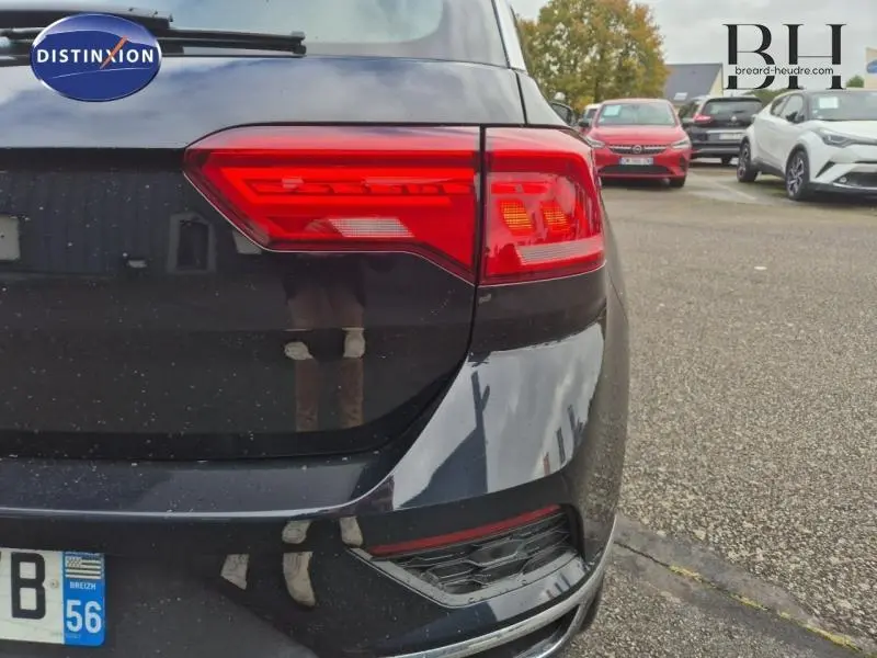 Gros plan sur le feu arrière droit d'un Volkswagen T-Roc gris Urano, avec une partie de la carrosserie arrière visible.