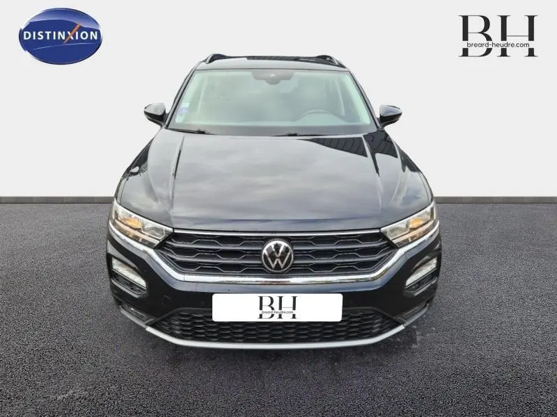 Vue frontale d'un Volkswagen T-Roc gris Urano avec calandre hexagonale et feux LED allumés.