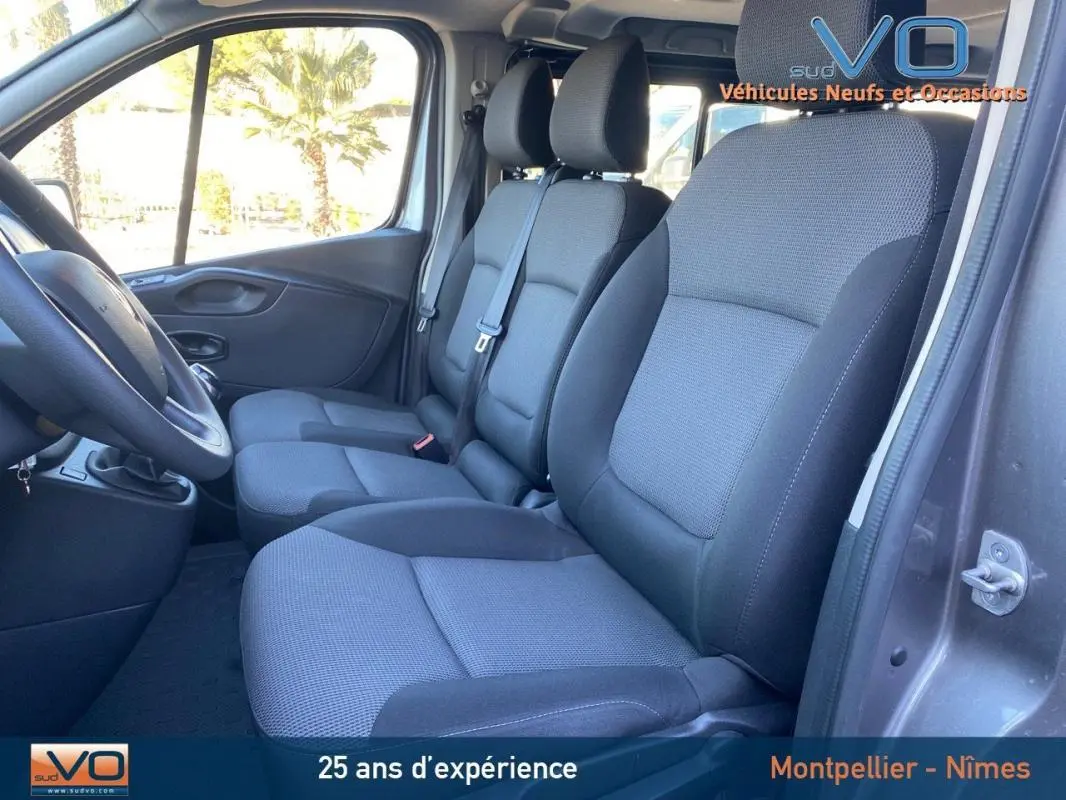 Intérieur du Renault Trafic Fourgon gris clair 2019, vue latérale sur les sièges avant en tissu gris et noir.
