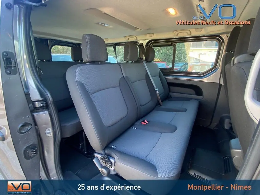 Intérieur du Renault Trafic Combi L2 gris clair, vue latérale sur la banquette arrière trois places avec porte latérale ouverte.