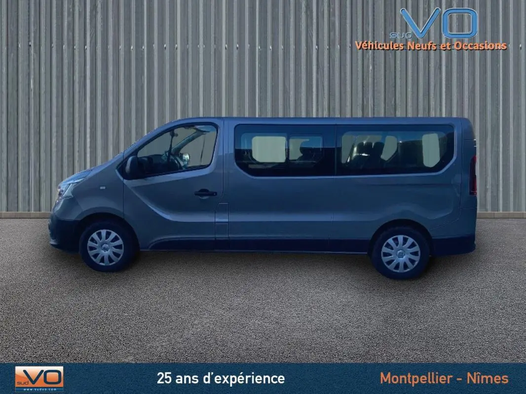 Profil côté gauche du Renault Trafic Combi gris clair 2019 avec grandes vitres latérales sur fond neutre.