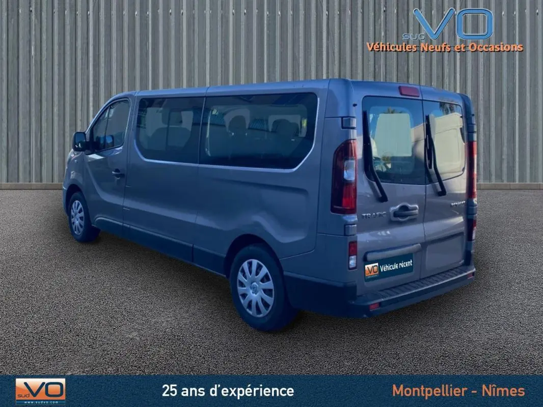 Renault Trafic Fourgon gris clair vu en 3/4 arrière droit avec vitres surteintées et porte latérale visible