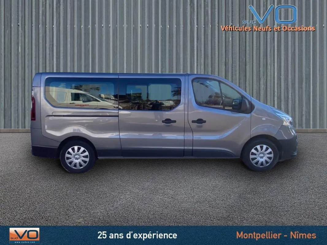 Profil droit du Renault Trafic Combi gris clair 2019 avec porte latérale et vitres surteintées visible en extérieur