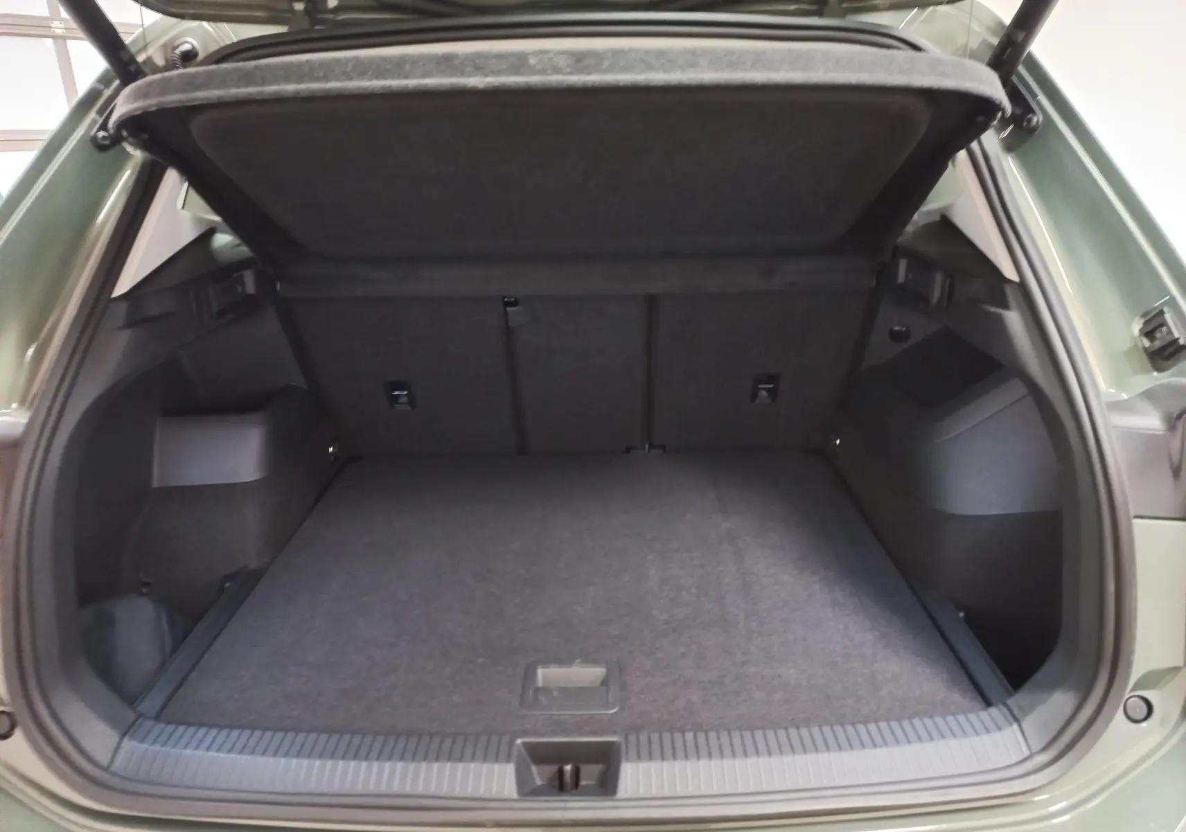 Coffre ouvert du Volkswagen Tiguan 2025 Vert Cipressino, vue arrière montrant l'espace de chargement vide.