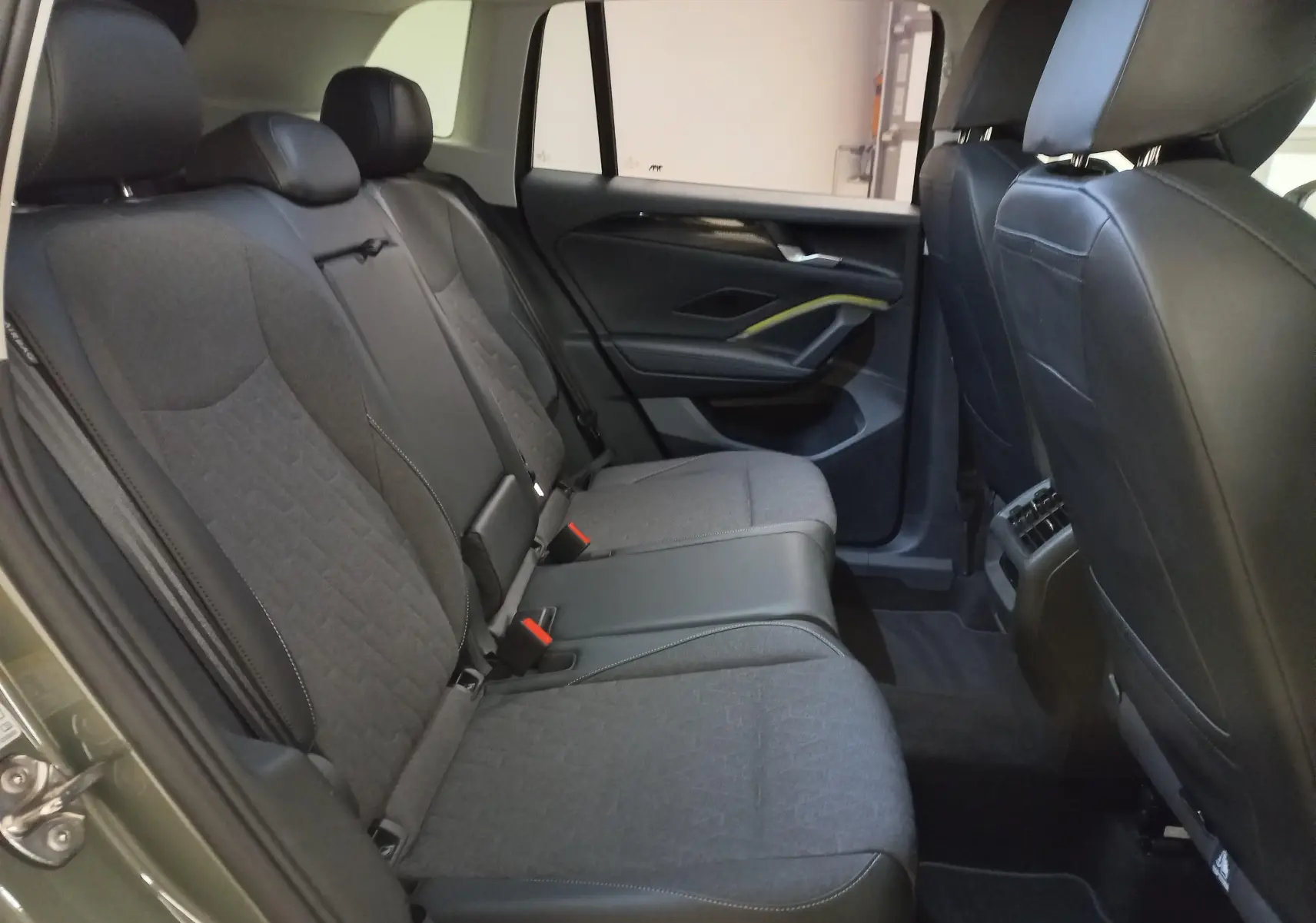 Vue intérieure arrière du Volkswagen Tiguan 2025, sièges tissu gris et cuir noir avec détails modernes sur la portière côté droit.