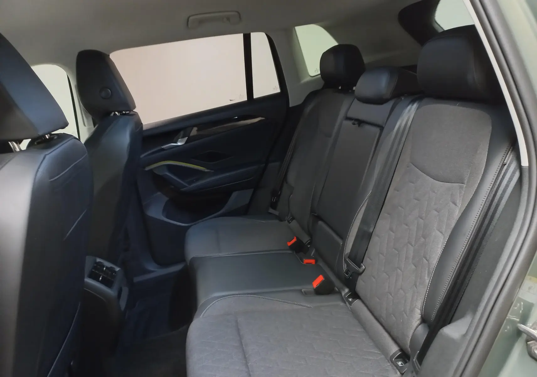 Vue intérieure arrière côté droit du Volkswagen Tiguan 2025 avec sièges en tissu noir et garnitures sombres.