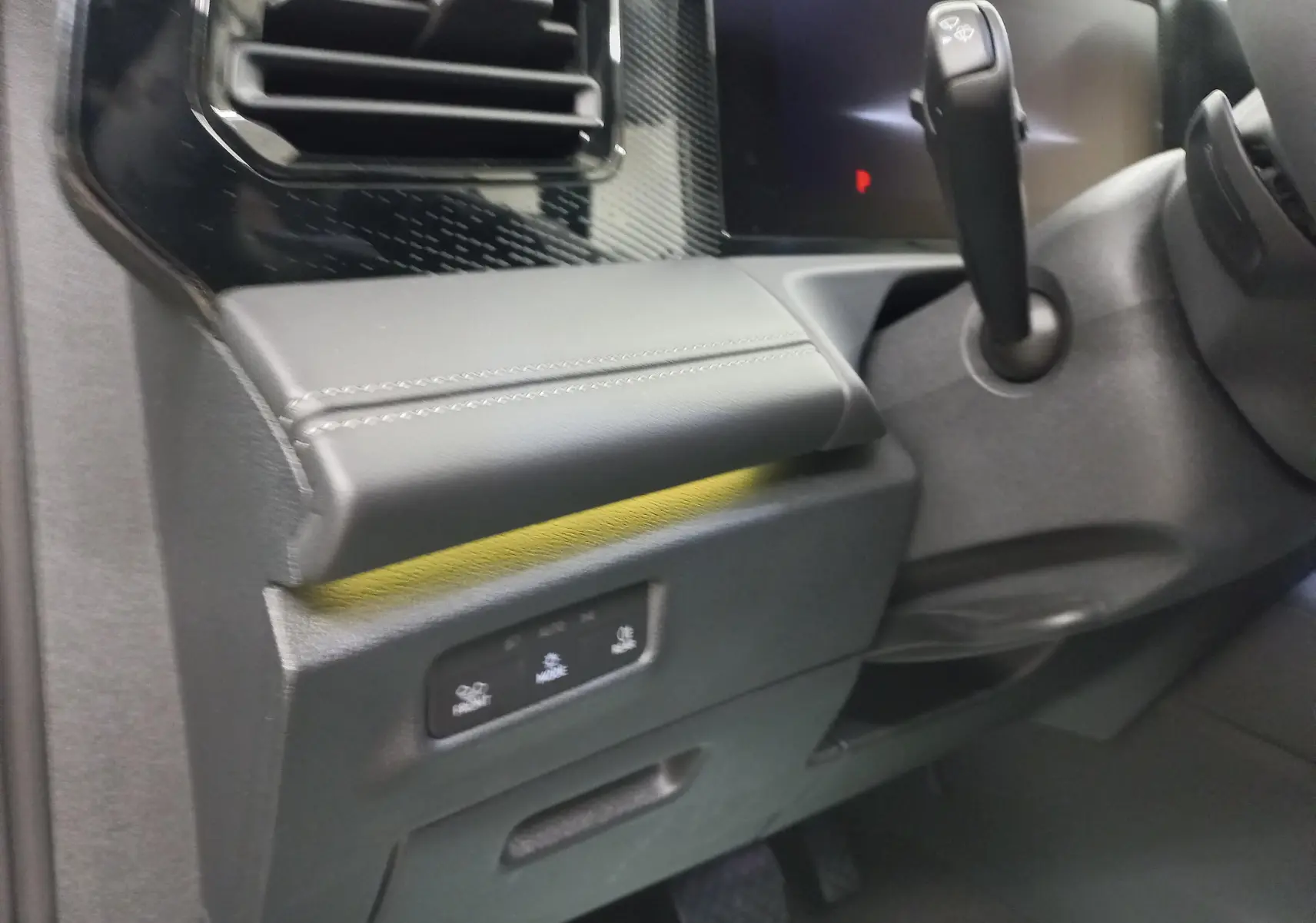 Gros plan sur la console côté gauche du Volkswagen Tiguan 2025, montrant la commande de boîte auto et les finitions en cuir noir.